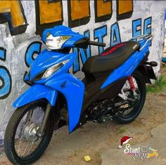 a blue motorcycle parked next to a graffiti covered wall