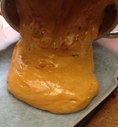 a person pouring batter into a bowl on top of a table with a knife and fork