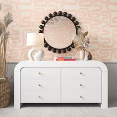 a white dresser topped with a mirror next to a lamp