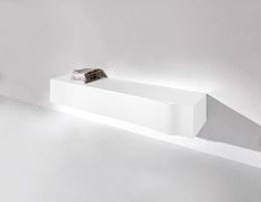 a white shelf that has some books on top of it and is lit up by the light coming from behind