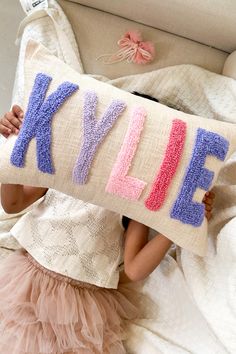 Perfect custom name pillow cover for the child's room. Imagine how wonderful this pillow cover will look propped up amongst the softies and the precious baby. Details of Listed Design: Fabric Frontside- Natural Textured Cotton Fabric Fabric Backside-  Cotton Baby Pink Size- 12x20 inch Font- Font A Yarn Colors- Periwinkle,Lavender,Baby Pink,Light Pink ------------ EMBROIDERY ------------ This is a hand punch needle work done in house by our talented artisans using crochet thread ----------- D E T Punch Needle Name Pillow, Punch Needle Pillows, Rainbow Room Decor, Kids Pillow, Name Pillow, Rainbow Pillow, Rainbow Room, Pink Embroidery, Crochet Thread