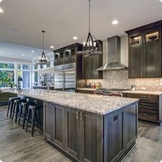 a large kitchen with marble counter tops and wooden flooring, along with stainless steel appliances