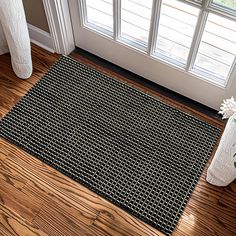 a black and white door mat sitting on top of a wooden floor next to a window