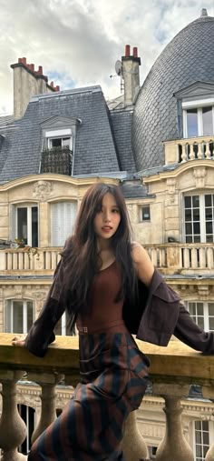 a woman standing on top of a balcony next to a building with two story windows