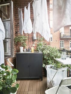 an apartment balcony with clothes hanging on the line and potted plants next to it