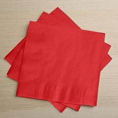 four red napkins sitting on top of a wooden table