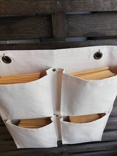 three pockets are hanging on the side of a wooden wall with paper sticking out of them