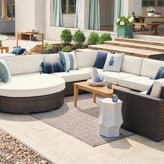 an outdoor living area with couches, tables and chairs on the ground near steps