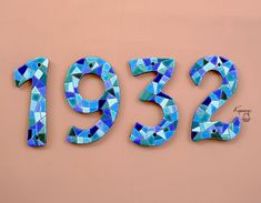 the numbers are made up of blue and green mosaic tiles on a pink wall,