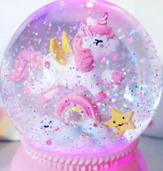 a pink snow globe with unicorns and stars on it