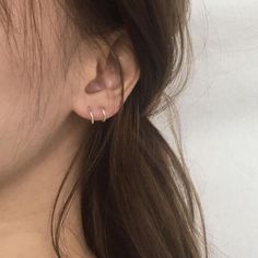 a close up of a woman's ear with two small hoops on it