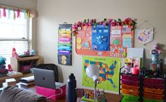 a desk with many different colored drawers in front of a laptop computer and other office supplies