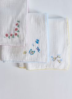 three embroidered napkins with flowers and butterflies on them