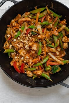 stir fry with chicken and vegetables in a skillet on a white table top, ready to be eaten