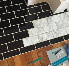 a bathroom with black and white tile on the floor next to a roll of toilet paper