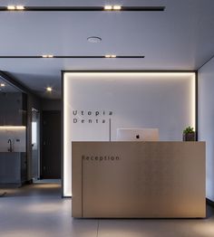 the reception desk is lit up by recessed lighting in this modern office space with white walls and flooring