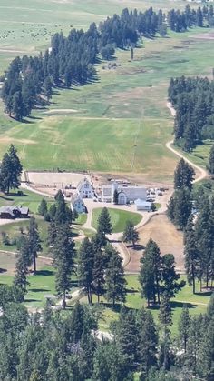 an aerial view of a large building surrounded by trees and grass in the middle of a field