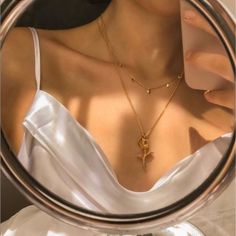 a close up of a woman's neck and necklace in a circular mirror with the reflection of her breast visible