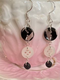 a pair of black and white earrings with buttons hanging from it's earwires