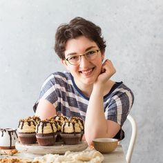 a person sitting at a table with some cupcakes