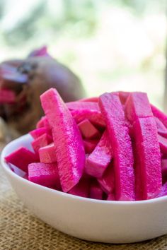 a white bowl filled with cut up pieces of beet sitting on top of a table