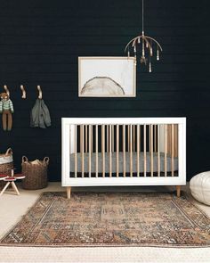 a baby's room with black walls and rugs on the floor, including a crib