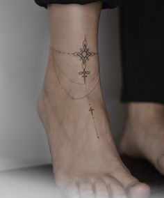 a woman's foot with a cross tattoo on the bottom of her left ankle