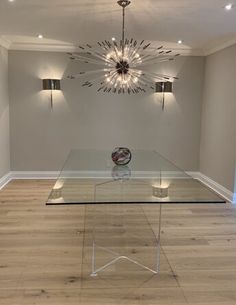 an empty room with a glass table and chandelier