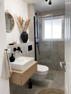 a white toilet sitting next to a walk in shower under a bathroom mirror above a sink