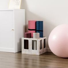 an exercise ball, yoga mat and other items on the floor next to a white cabinet