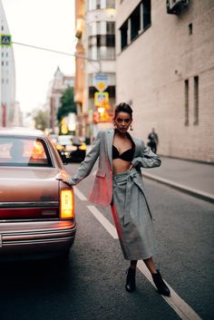 a woman standing next to a car in the street