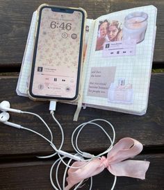 an open cell phone sitting on top of a wooden table next to ear buds and headphones