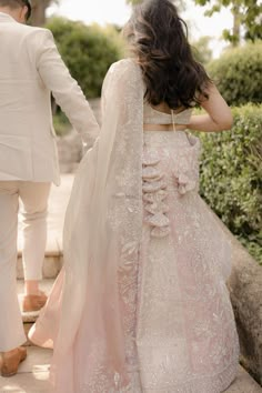 a bride and groom walking down the steps together in their wedding outfits, with one holding the hand of the other's hand