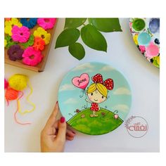 a person holding a plate with a cartoon girl on it next to some crafting supplies