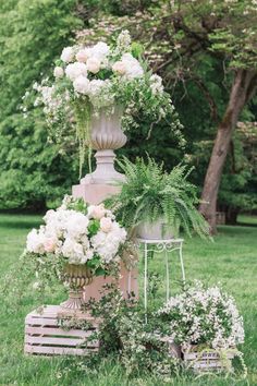 a tall cake with flowers and greenery on it in the middle of a field