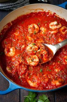 shrimp and tomato sauce in a skillet with a ladle scooping up some