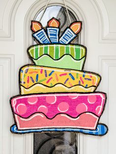 a colorful cake hanging from the side of a white door with a glass window behind it