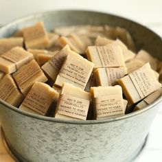 a metal bucket filled with lots of brown and white pieces of soap sitting on top of a wooden table