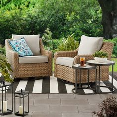 two wicker chairs sitting on top of a patio next to a table with candles