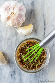 garlic and herbs in a jar on a marble counter top with an onion wedge next to it