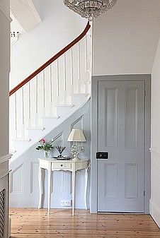 a white table sitting under a chandelier next to a stair case in a house