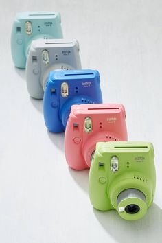 four different colored cameras lined up on a white surface