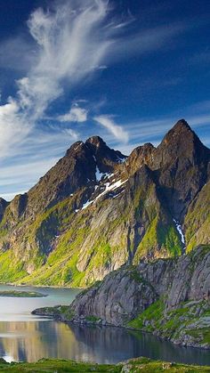 the mountains are covered in snow and green grass, while water is still below them