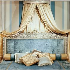 a bed with four pillows on it in front of a curtained headboard and drapes