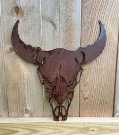 a metal bull's head mounted to a wooden fence with rusted paint on it