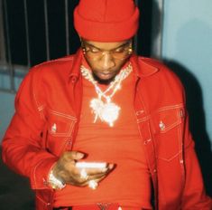 a man in a red jacket looking at his cell phone while wearing a red hat