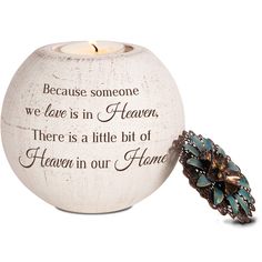 a white candle holder with a quote on it and a blue flower in the center