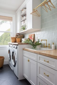 a washer and dryer in a white kitchen with wood counter tops on the counters