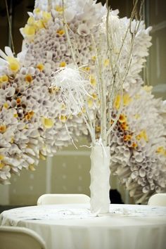 a white vase filled with flowers sitting on top of a round table next to chairs