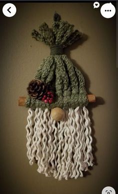 a knitted christmas stocking hanging on the wall with pine cones and other decorations